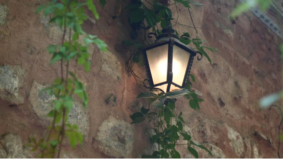 A vintage lantern outdoor wall light with warm glow, complementing rustic stone walls.